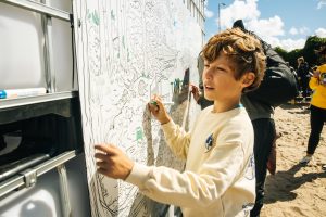 Vaikas piešia aplinkosaugos veiklų erdvėje